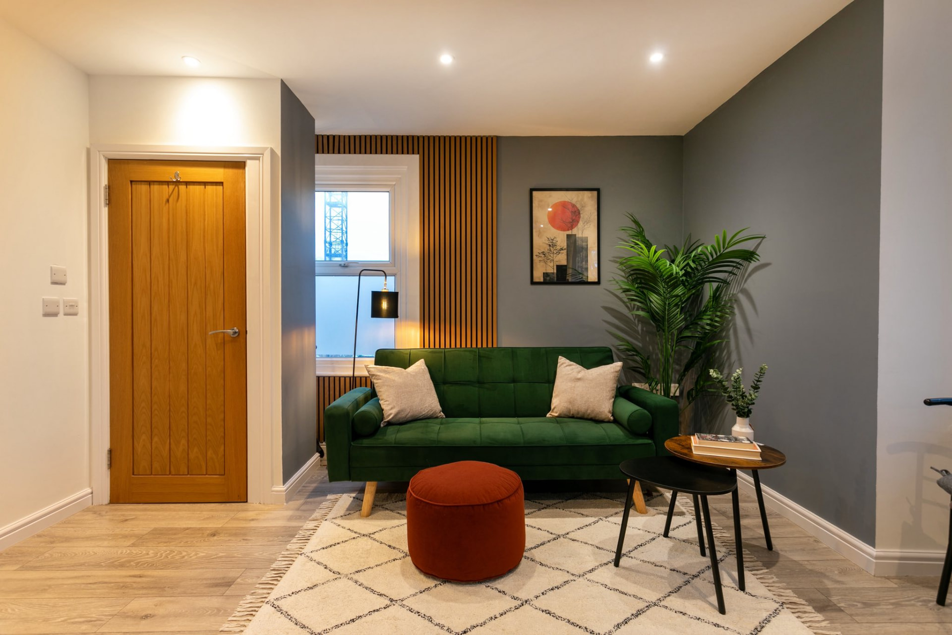 Living room with an upholstered sofa and slatted timber wall detailing.