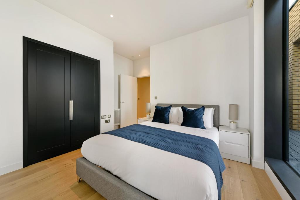 Bedroom with built-in wardrobes and a window onto a neighbouring building.